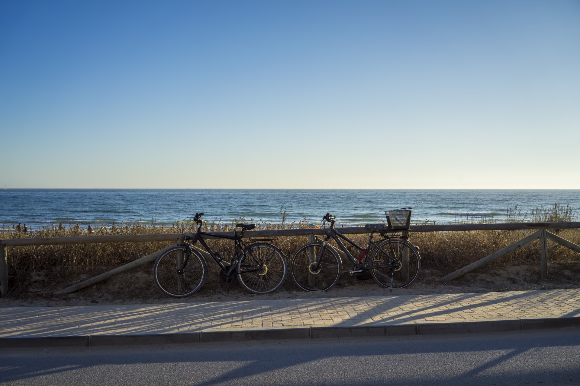 beautiful-shot-bicycles-near-empty-street-with-sea-background
